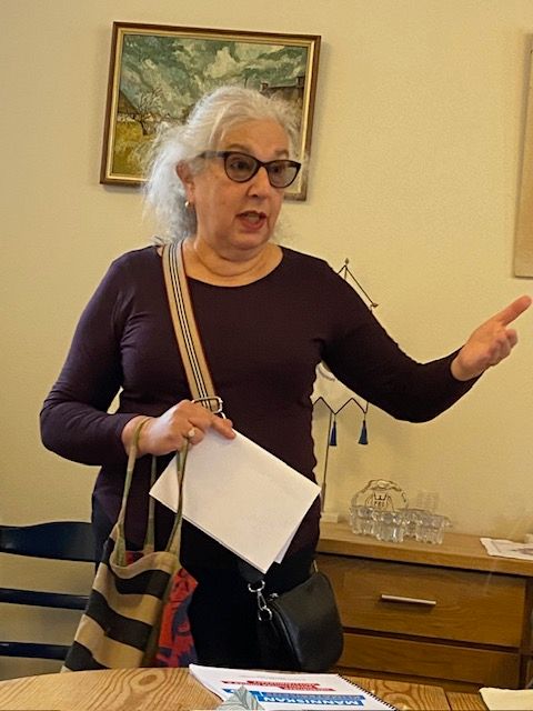 Portrait of Anna G&ouml;nberg with a painting, chest of drawers and table in the background.
