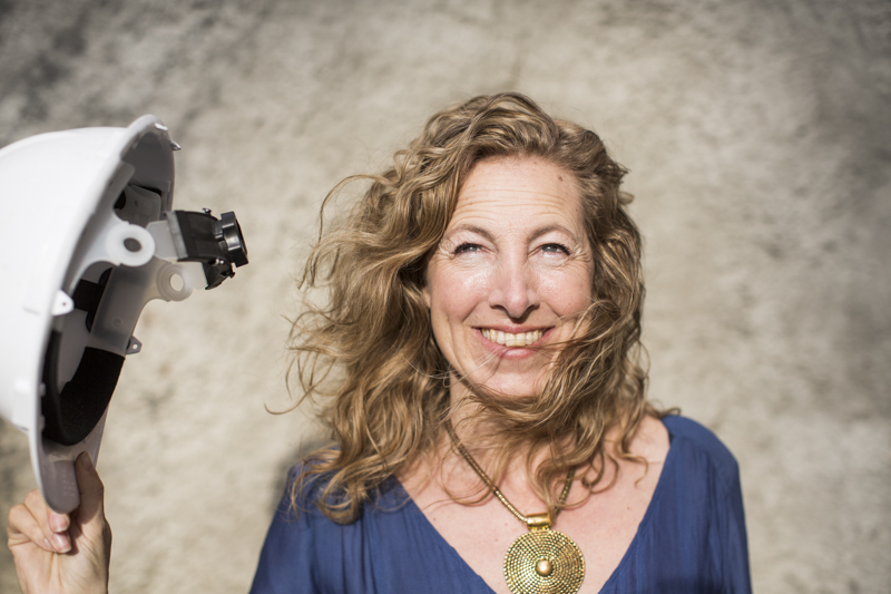 Portrait of Ingrid Westman holding a white helmet with a brown background.