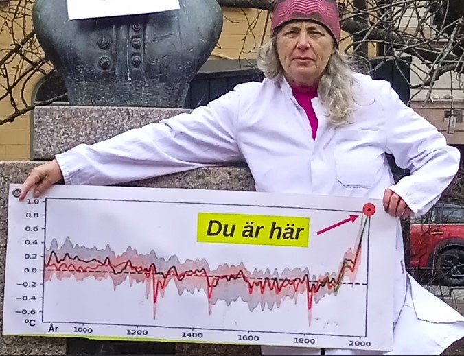 Portrait of Janine Okeefe holding a graph showing the rise in temperature caused by humans.