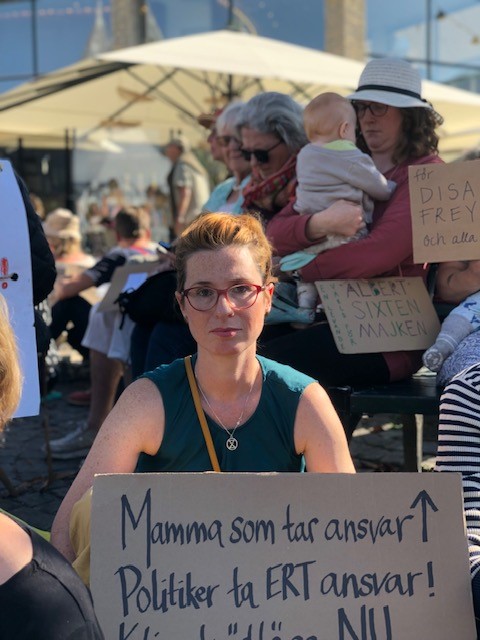 Portrait of Tatjana Boric holding a sign that says “Mamma som tar ansvar, politiker ta ert ansvar!”